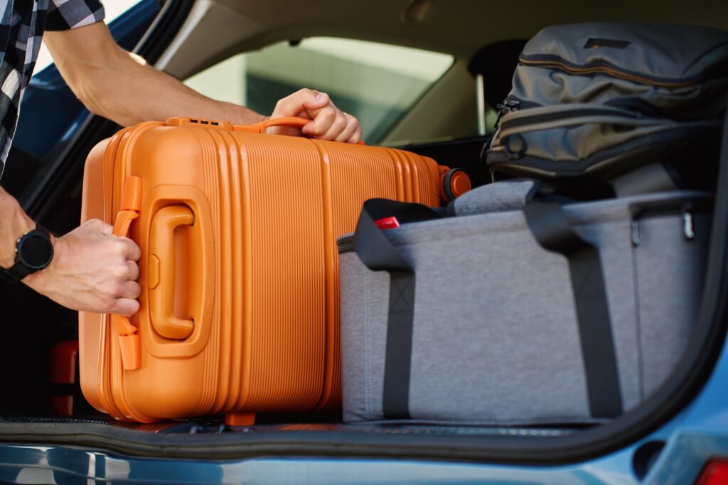 Man loading suitcase into car trunk, Packing luggage for travel