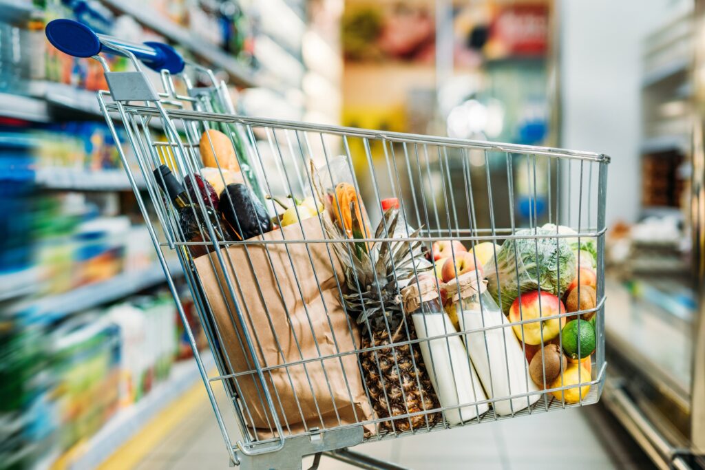 selective focus of shopping cart with purchases in supermarket